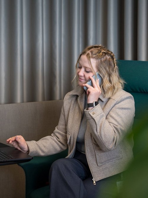 SIWA CISO und ISO 27001 Expertin, sitzt auf einem grünen Lounge Sessel und telefoniert